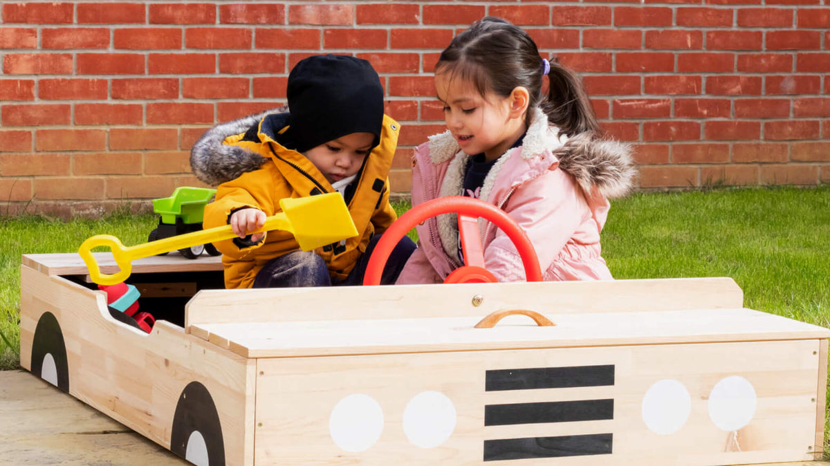 Children playing in a car shaped sandpit