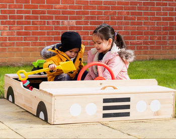 Children playing in a car shaped sandpit