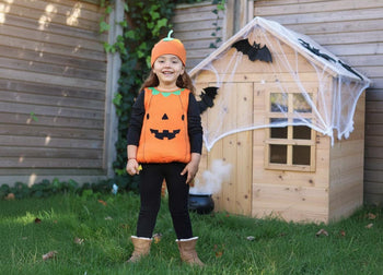 A child dressed as a pumkin for Halloween in from of her decorated playhouse